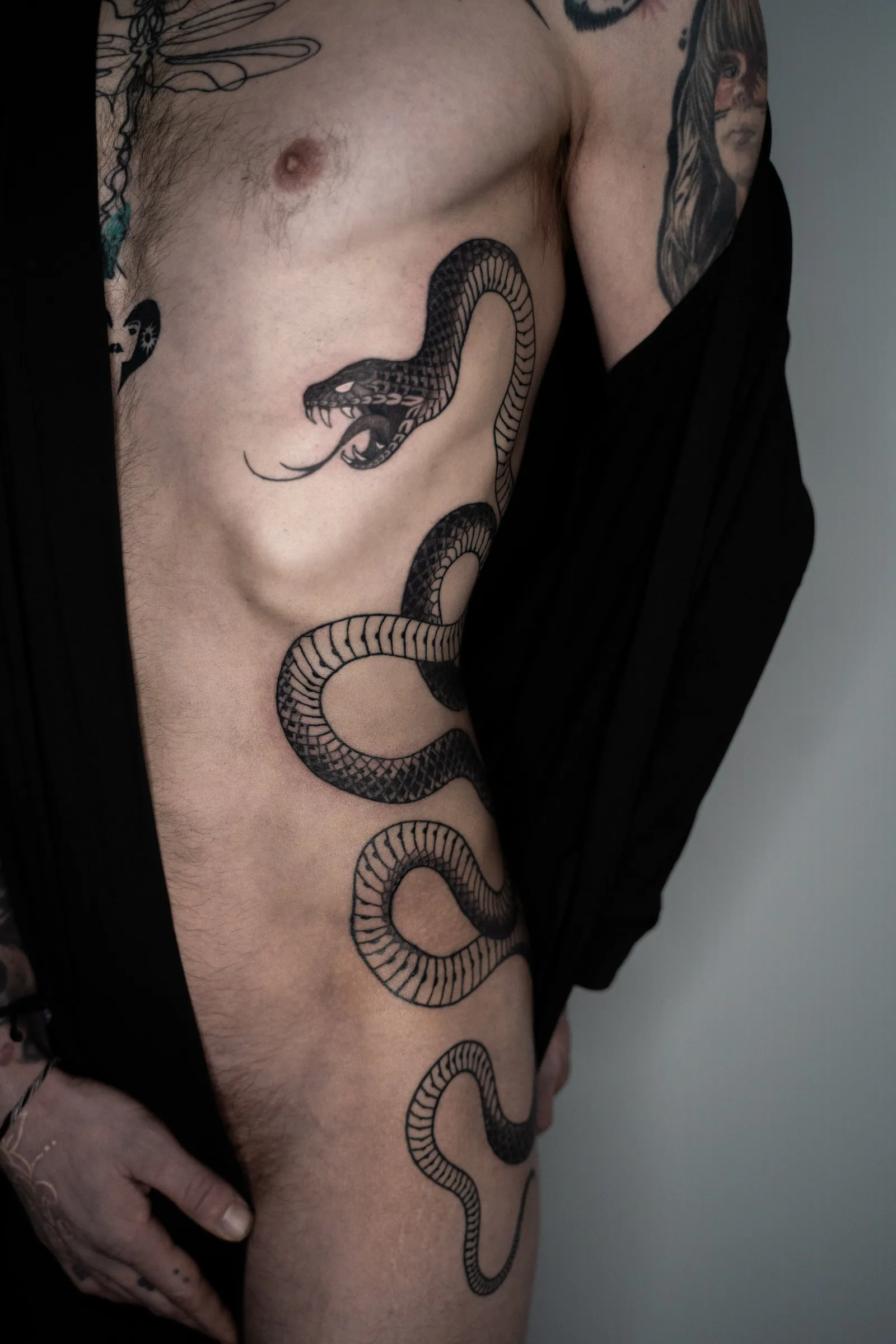 The snake seen from the front, its body coiling down the ribs and over the hip