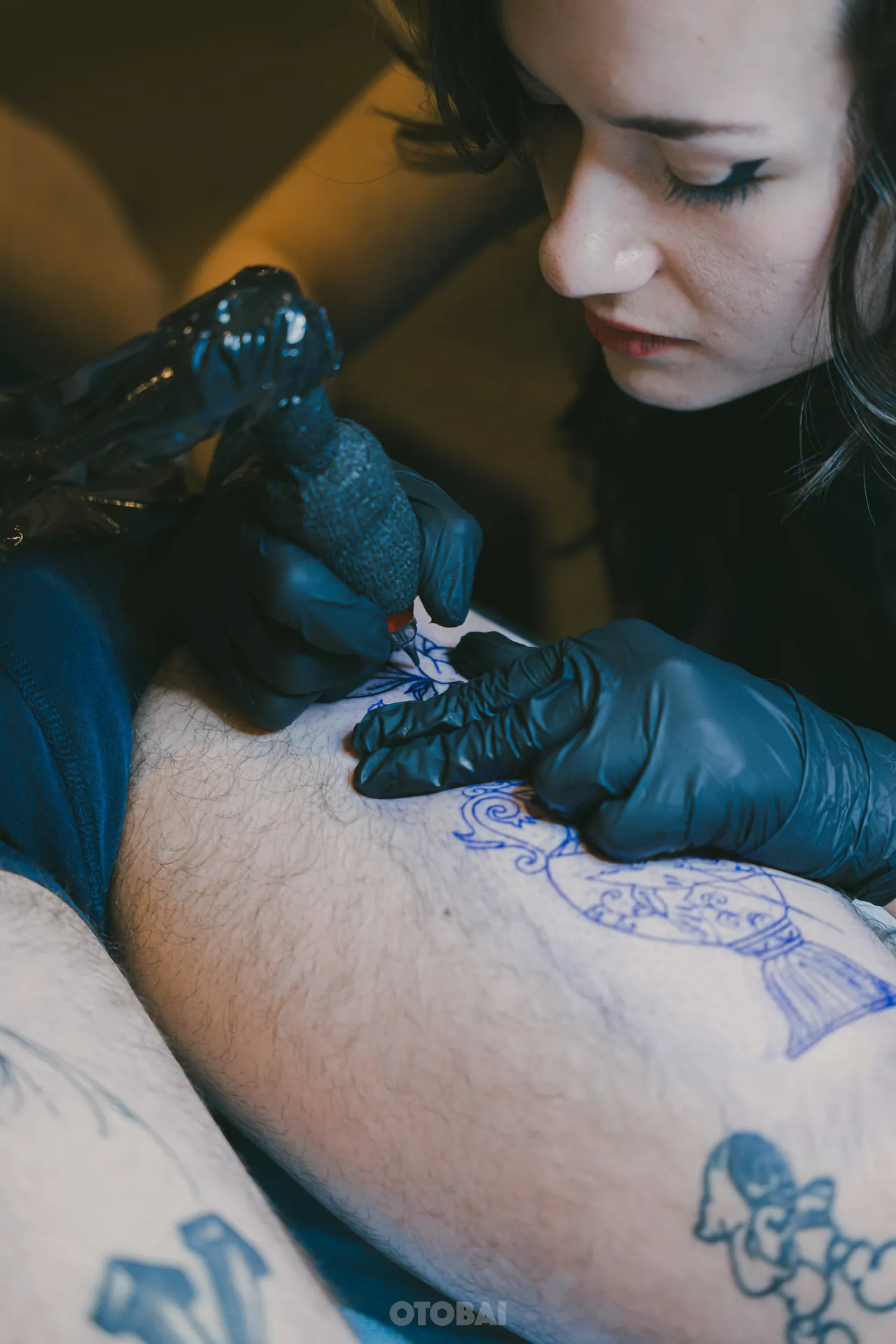 Joy lining a tattoo on a leg over its violet stencil