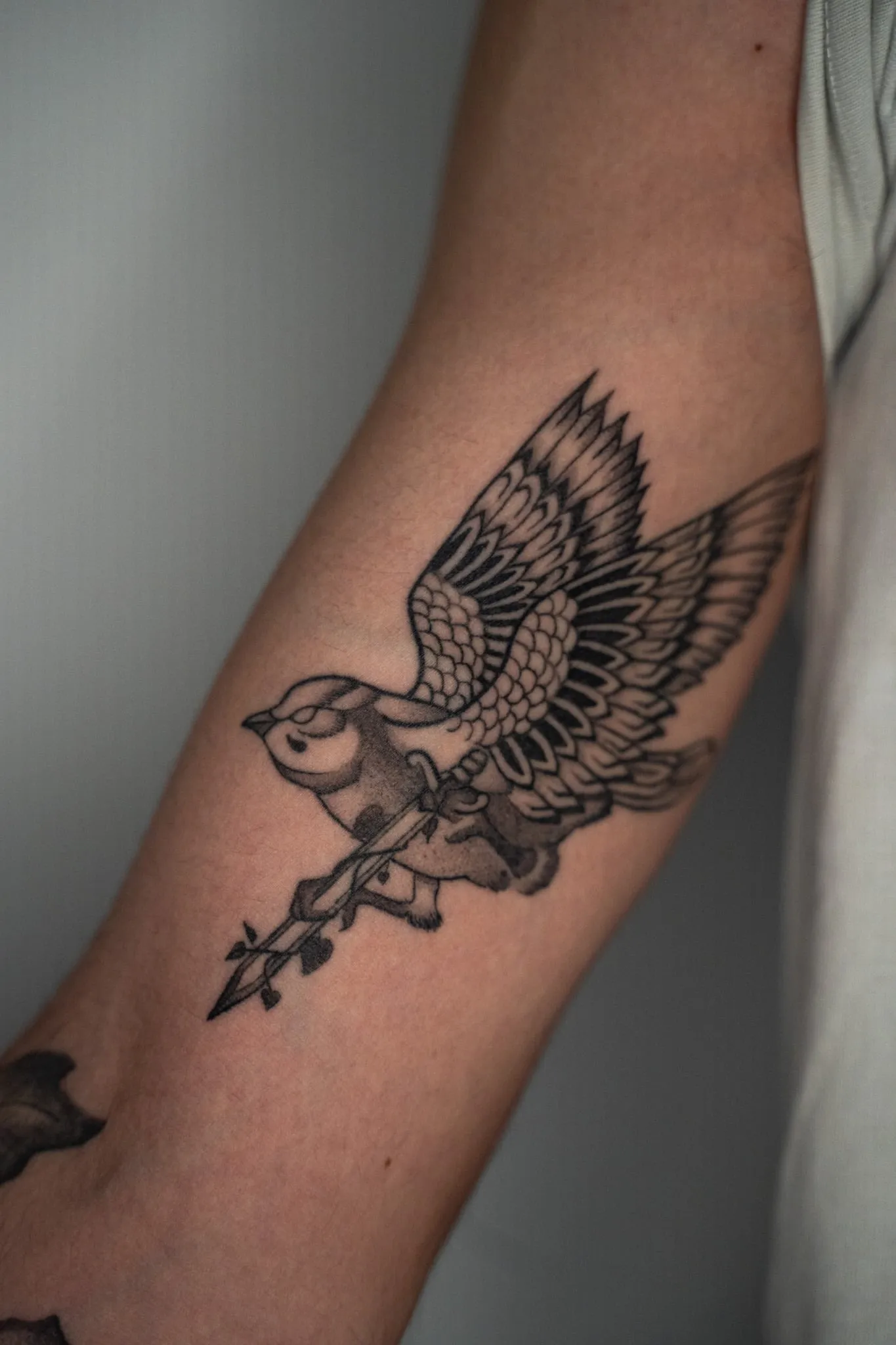 A sparrow in flight crossed by a dagger, on a forearm, healed